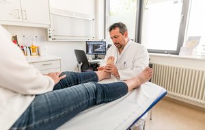 Ein Arzt überprüft den Fuß eines Patienten am Bett