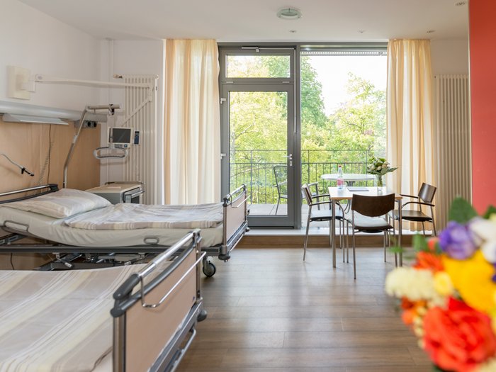 Ein Modernes Doppel-Krankenzimmer mit Blumen und großen lichtspendenden Fenstern